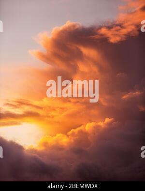 Schöner farbenprächtiger Sonnenuntergang in Orange, Gelb und Rosa, der durch die Wolken am Himmel brennt Stockfoto