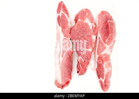 Rohes Schweinefleisch auf weißem Brett Nahaufnahme isoliert auf weißem Hintergrund. Frische drei Scheiben ohne Knochen, Draufsicht. Stockfoto