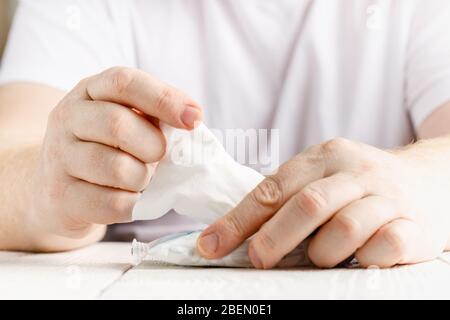 Nahaufnahme auf der Mitte der Hände Mann wischen mit weißem Alkohol Tissue Reinigung Serviette Desinfektion von Viren und Bakterien im Tag zu Hause oder im Büro Stockfoto
