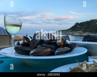 Gekochte Muscheln mit einem Glas Weißwein. Stockfoto