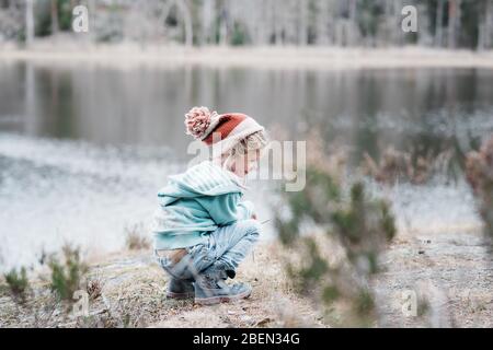 Junges Mädchen, das auf einem Felsen sitzt und lächelt, während es in Schweden wandert Stockfoto