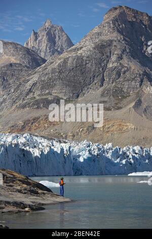 Mann, der am Ufer eines Fjords in Grönland steht Stockfoto