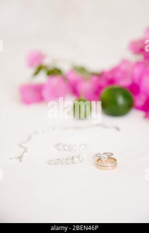 Eheringe und Schmuck. Auf weißem Hintergrund und rosa Bougainvillea Blätter und Limette. Stockfoto
