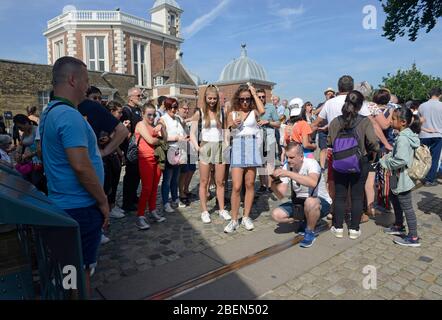 Die Besucher fotografieren auf der Greenwich Meridian Linie am Greenwich Royal Observatory in London, Großbritannien Stockfoto