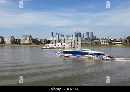 Eine Flussfähre fährt vom Pier in Greenwich, London, UK, stromaufwärts, mit den Gebäuden von Canary Wharf im Hintergrund. Stockfoto