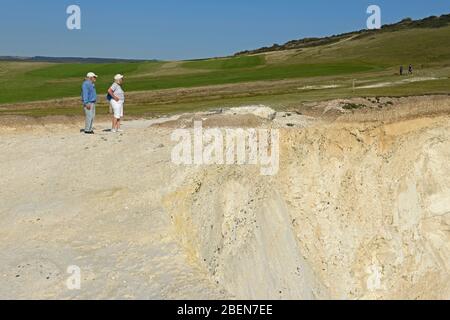 Ein Paar entscheidet sich für ihre nächsten Schritte auf dem Weg auf einer Klippe bei Seaford Head in East Sussex, Großbritannien Stockfoto