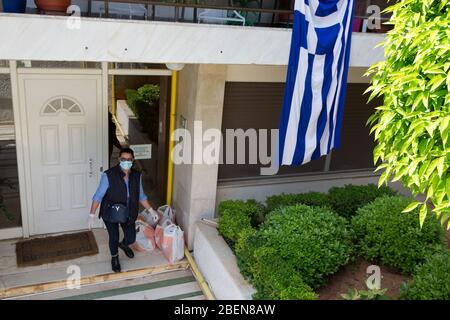 Athen, Griechenland. April 2020. Ein Mitarbeiter des Programms "Help at Home" der Gemeinde Nea Smyrni liefert am 14. April 2020 das Wesentliche in ein Wohnhaus in Athen, Griechenland. Nach der Pandemie hat die griechische Regierung das Programm "Hilfe zu Hause" verstärkt, um die schwächsten Mitglieder der griechischen Gesellschaft zu unterstützen. ZU "Feature: Griechenland stärkt Programm "Help at Home" zur Unterstützung verletzlicher Bürger während der COVID-19-Krise" Quelle: Marios Lolos/Xinhua/Alamy Live News Stockfoto