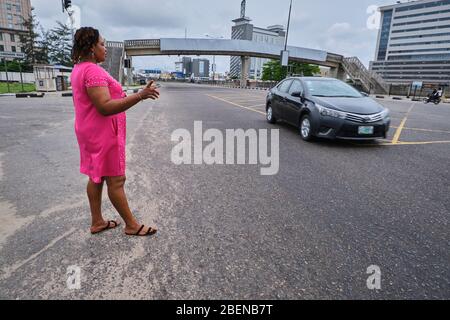 Eine Frau versucht, während der Sperrung von Covid-19 in Lagos, Nigeria, ein Auto zu flaggen. Stockfoto