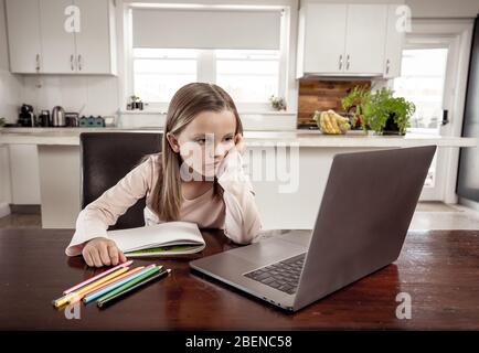 Ausbruch Des Coronavirus. Sperrung und Schließung von Schulen. Schulmädchen mit Gesichtsmaske, die Online-Schulklassen beobachtet, die sich zu Hause gelangweilt und depressiv fühlen. C Stockfoto