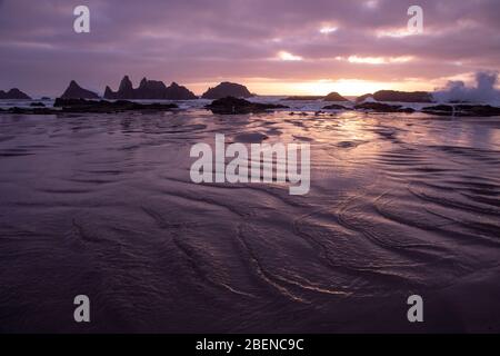 Wellen schlagen über natürlichen Felsen während des Sonnenuntergangs in Seal Rock, Oregon Stockfoto