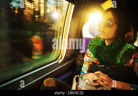 Eine offene Aufnahme einer jungen, schönen Pariser Frau, die in einem Zug unterwegs ist und am Fenster sitzt Stockfoto