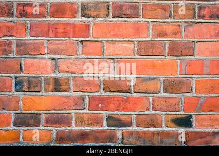 Detaillierte Nahaufnahme der roten Ziegelwand in einem alten und verwitterten Gebäude, rote Ziegelwand Textur Stockfoto