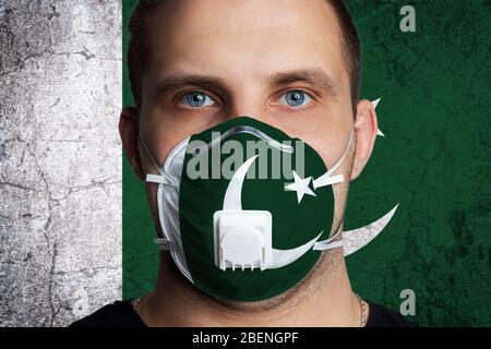 Junger Mann mit Wunden Augen in einer medizinischen Maske in den Farben der Nationalflagge von Pakistan gemalt. Coronovirus-Krankheit COVID-19 Konzept. Der Mensch ist afra Stockfoto