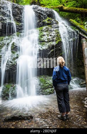 Eine Frau steht unter Cascade Falls im Moran State Park, Orcas Island, Washington, USA. Stockfoto