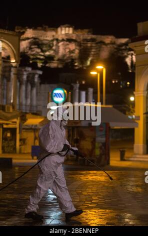 Athen, Griechenland. April 2020. Ein Gemeindearbeiter sprüht am 14. April 2020 Desinfektionsmittel auf dem Monastiraki-Platz am Fuße der Akropolis in Athen, Griechenland. Griechenland befindet sich seit März 23 in einer landesweiten Lockdown-Zeit, die am 27. April endet. Nach der jüngsten Zählung durch das Gesundheitsministerium am Dienstag, die Gesamtzahl der COVID-19-Infektionen im Land jetzt bei 2,170 und die Todesrate ist auf 101 gestiegen. Kredit: Marios Lolos/Xinhua/Alamy Live News Stockfoto