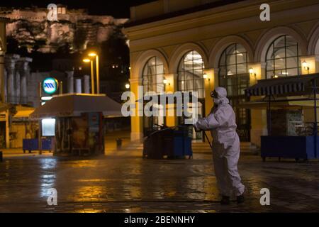 Athen, Griechenland. April 2020. Ein Gemeindearbeiter sprüht am 14. April 2020 Desinfektionsmittel auf dem Monastiraki-Platz am Fuße der Akropolis in Athen, Griechenland. Griechenland befindet sich seit März 23 in einer landesweiten Lockdown-Zeit, die am 27. April endet. Nach der jüngsten Zählung durch das Gesundheitsministerium am Dienstag, die Gesamtzahl der COVID-19-Infektionen im Land jetzt bei 2,170 und die Todesrate ist auf 101 gestiegen. Kredit: Marios Lolos/Xinhua/Alamy Live News Stockfoto