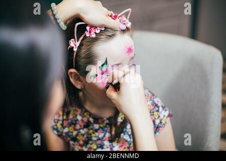 Mädchen zeichnet kleine Mädchen Aqua Make-up. Gesichtsbemalung. Kinder Freizeit Stockfoto