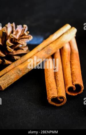 Zimtstangen mit Kegel auf schwarzem Hintergrund, weihnachtsgewürze Stockfoto