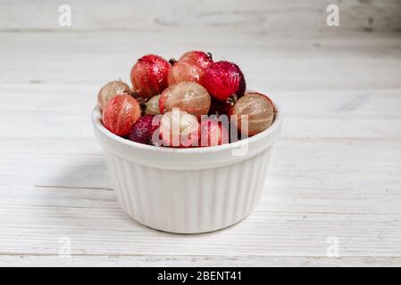 Set aus Bio-Stachelbeere mit kleinen Muffins. Stachelbeeren Früchte in einer Tasse. Rote Stachelbeere auf rustikalem Holzhintergrund. Süße und saftige Beere. Oben V Stockfoto