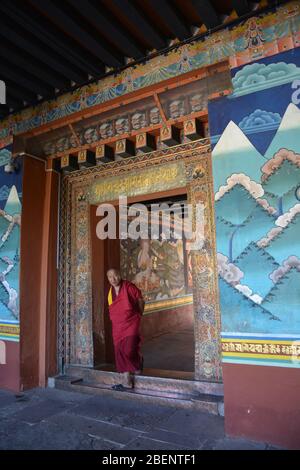 Ein buddhistischer Mönch tritt durch eine Tür am historischen Punakha Dzong (Palast und Festung) in Bhutan, das aus dem Jahr 1637 stammt. Stockfoto