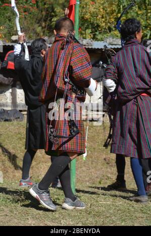 Männer in traditioneller Kleidung nehmen an einem Bogenschießen Wettbewerb in einem kleinen Dorf in der Nähe von Punakha, Bhutan Stockfoto