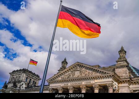 Berlin, Deutschland. April 2020. 04/09/2020, Berlin, das Berliner Reichstagsgebäude von Baumeister Paul Wallot am Platz der Republik an einem sonnigen Frühlingssafttag mit bewölktem Himmel. Detail des Gebäudes mit dem Schriftzug 'dem Deutschen Volk' und der winkenden deutschen Flagge. Der Reichstag ist Sitz des Deutschen Bundestages mit Plenarbereich. Kredit: dpa/Alamy Live News Stockfoto