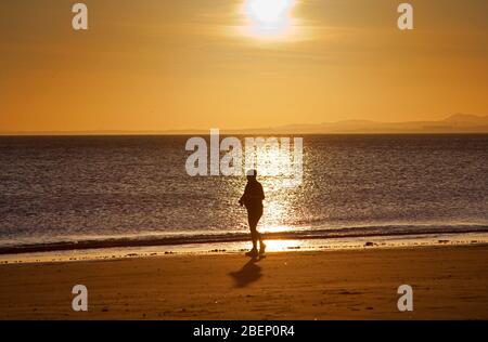 Portobello Beach, Edinburgh, Schottland, Großbritannien. April 2020. Eine Frau war früh am Strand, um den Sonnenaufgang über dem Firth of Forth zu sehen und ihr tägliches Training zu erlauben. Temperatur 6 Grad Stockfoto