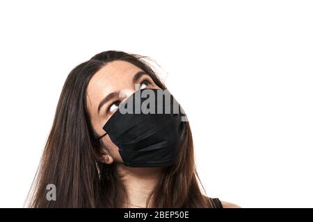 Ein Nahaufnahme-Porträt einer hübschen Frau, die eine chirurgische Maske auf weißem Hintergrund isoliert trägt Stockfoto