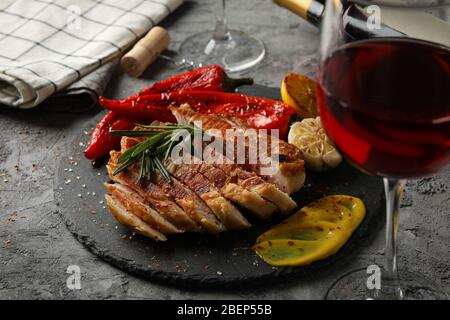 Gehacktes gebratenes Schweinefleisch Steak, Gemüse und Wein auf grauem Hintergrund. Grillgerichte Stockfoto