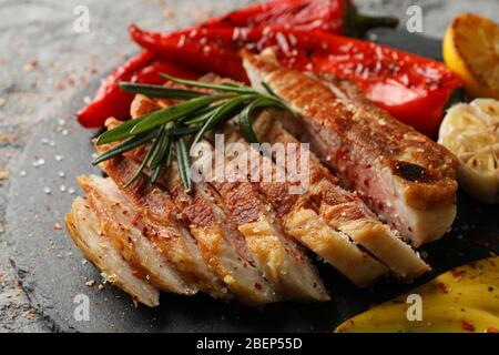 Tablett mit gehacktem Schweinefleisch Steak und Gemüse auf grauem Hintergrund. Grillgerichte Stockfoto