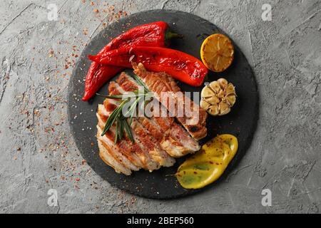 Tablett mit gehacktem Schweinefleisch Steak und Gemüse auf grauem Hintergrund. Grillgerichte Stockfoto