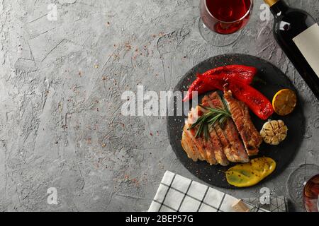 Gehacktes gebratenes Schweinefleisch Steak, Gemüse und Wein auf grauem Hintergrund. Grillgerichte Stockfoto