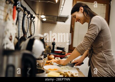 Junge Hausfrau Anfänger kochen Schneiden Zwiebel.Schneiden Zwiebeln auf einem Schneidebrett.Schneiden, würfeln und zerhacken Zwiebel.Vorbereitung zum Kochen. Gesunde Ernährung und li Stockfoto