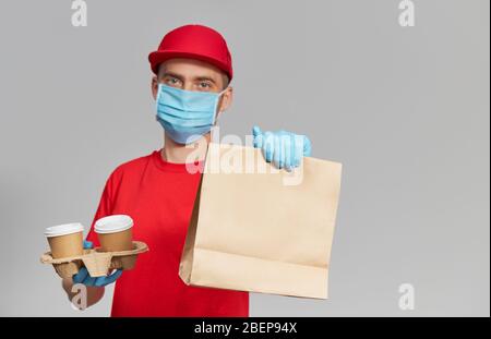 Kurier in Schutzmaske und medizinischen Handschuhen liefert Essen und Kaffee zum Mitnehmen. Lieferservice unter Quarantäne. Platz für Text kopieren Stockfoto