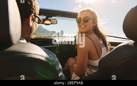 Rückansicht des Paares, das in einem Auto unterwegs ist. Mann und Frau, die in einem Cabrio auf eine Reise gehen. Stockfoto