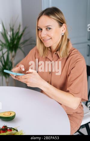 Lächelnde Frau, die frisches Obst und Gemüse mit dem Smartphone fotografiert Stockfoto