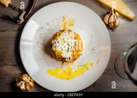 Gelbes Kurkuma-Risotto mit wilden Steinpilzen Platte mit Rotwein serviert.Safranreis mit Parmesan-Käse.Italienische traditionelle Rezepte mit Wein Stockfoto