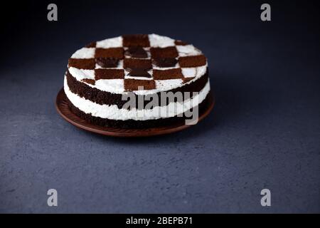 Biskuitkuchen mit Buttercreme. Kuchen in Form eines Schachbretts. Ein Geschenk für den Tag eines Schachspielers. Kuchen mit Schokoladenkuchen und weißem Pudding. Stockfoto