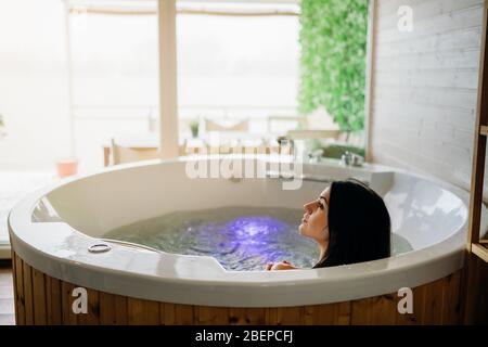 Frau mit einem Spa Tag Moment in modernen Bad indoor.Relaxing zu Hause in der Whirlpool-Badewanne.Indoors Jacuzzi Tub.Leisure activity.Self care.Body nou Stockfoto