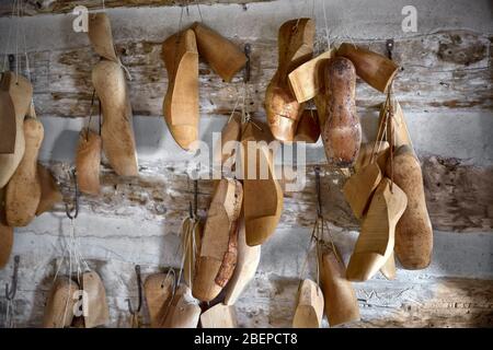 Verschiedene Vintage Holzschuhe halten in einer Reihe an den alten Wänden der Werkstatt Stockfoto