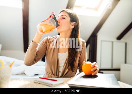 Frau im Home Office trinken Orange aromatisierte Aminosäure Vitamin Powder.Keto supplement.After Übung flüssige meal.Weight Loss Fitness Ernährung Diät. Stockfoto