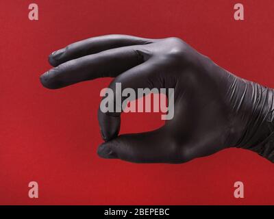 Hand in schwarzen Schutzhandschuh mit OK-Schild. Auf rotem Hintergrund Stockfoto