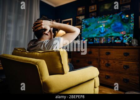 Adolescent professionelle esport Gamer mit Kopfhörern spielen und verlieren wettbewerbsfähige Internet MMORPG Cyber-Turnier in Ego-Shooter-Strategie Stockfoto