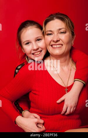 Mutter und Tochter in rotem Kleid kuscheln Familie Stockfoto