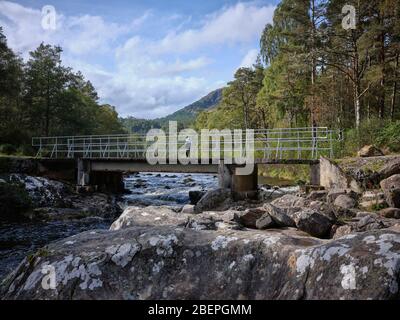 Glen Affric, Beauly, Inverness-Shire, Schottland, Großbritannien. 24/09/19. Ein Wanderer bewundert die Aussicht flussaufwärts auf die Brücke über den Fluss Affric bei Dog Falls. Stockfoto