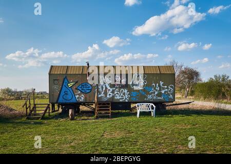 Ein alter Bautrailer mit Graffiti-Kunstwerken in der einsamen Landschaft Stockfoto