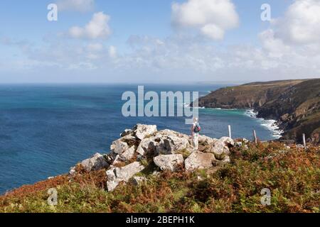 Frau auf einem felsigen Felsen stehend, die die atemberaubende Küstenlandschaft nahe St Ives in Cornwall, England, Großbritannien, betrachtet Stockfoto