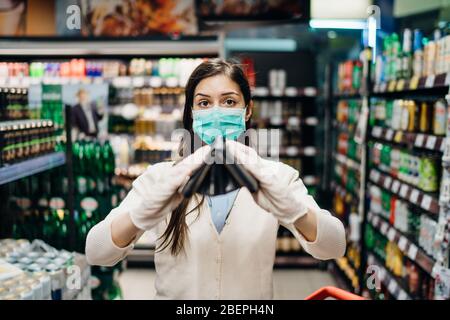 Besorgte Frau mit Maske Lebensmittel einkaufen im Supermarkt Blick auf leere Brieftasche.nicht genug Geld, um Lebensmittel zu kaufen.Covid-19 Quarantäne sperren.Financial Stockfoto