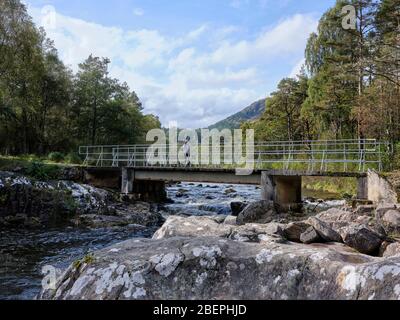 Glen Affric, Beauly, Inverness-Shire, Schottland, Großbritannien. 24/09/19. Ein Wanderer bewundert die Aussicht flussabwärts von Bridge over River Affric bei Dog Falls. Stockfoto