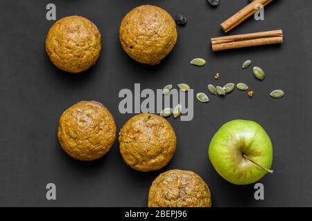 Muffins auf schwarzem Hintergrund mit Apfel, Zimt-Rosinen und Kürbiskernen - Draufsicht Stockfoto